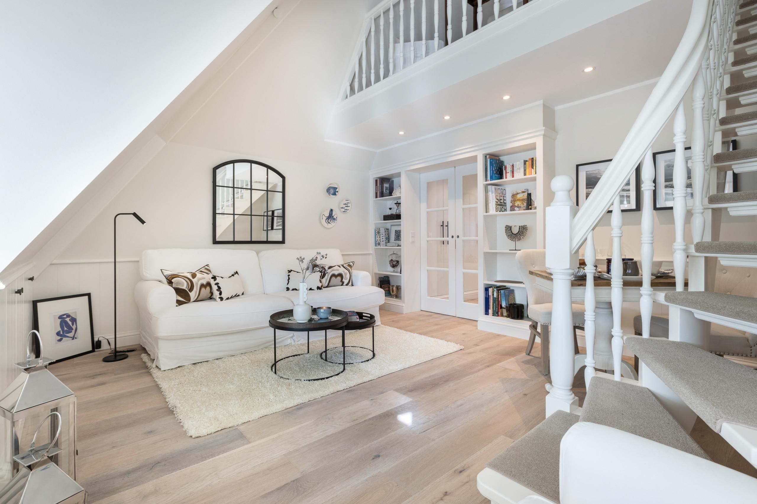 Wohnbereich mit Sofa und Treppe in Ferienwohnung auf Sylt